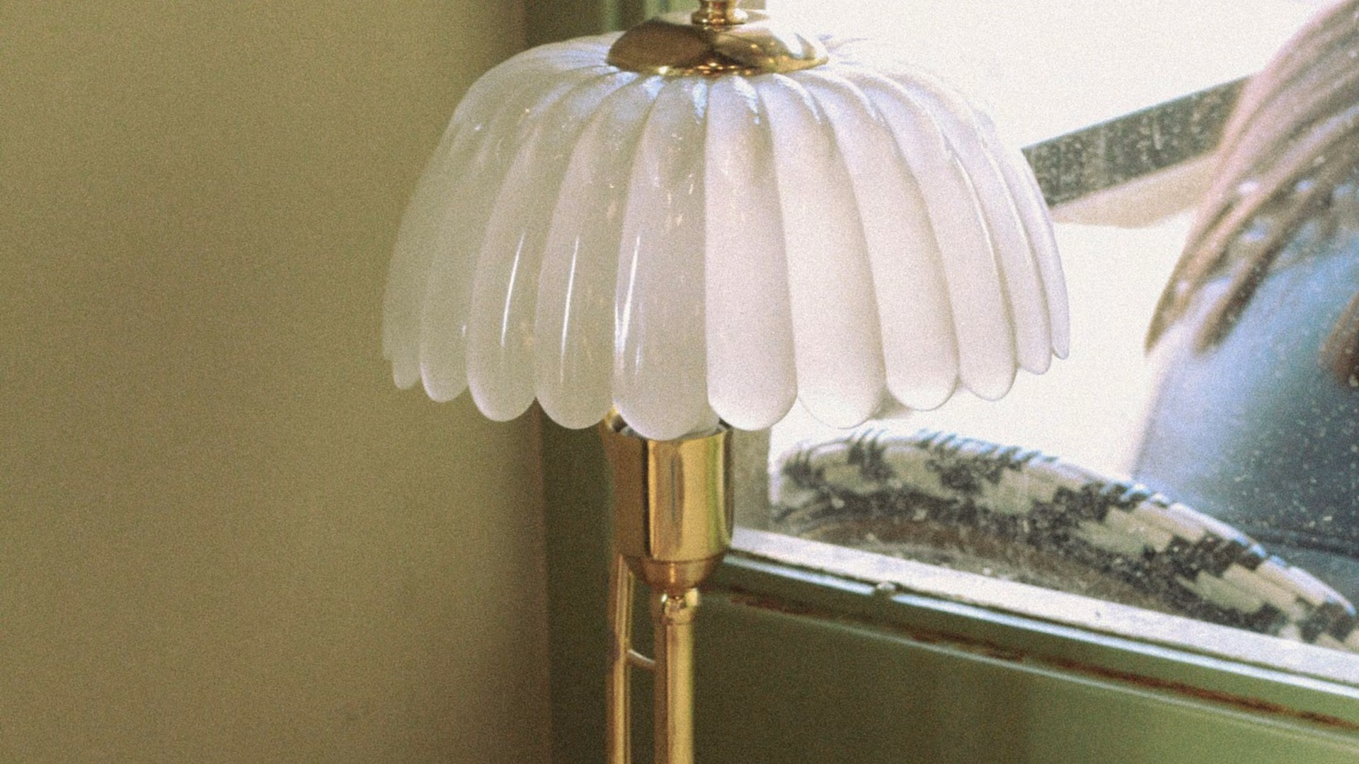 Licensed stock photo (illustrative): fluted glass shade on a brass lamp beside a sunny window