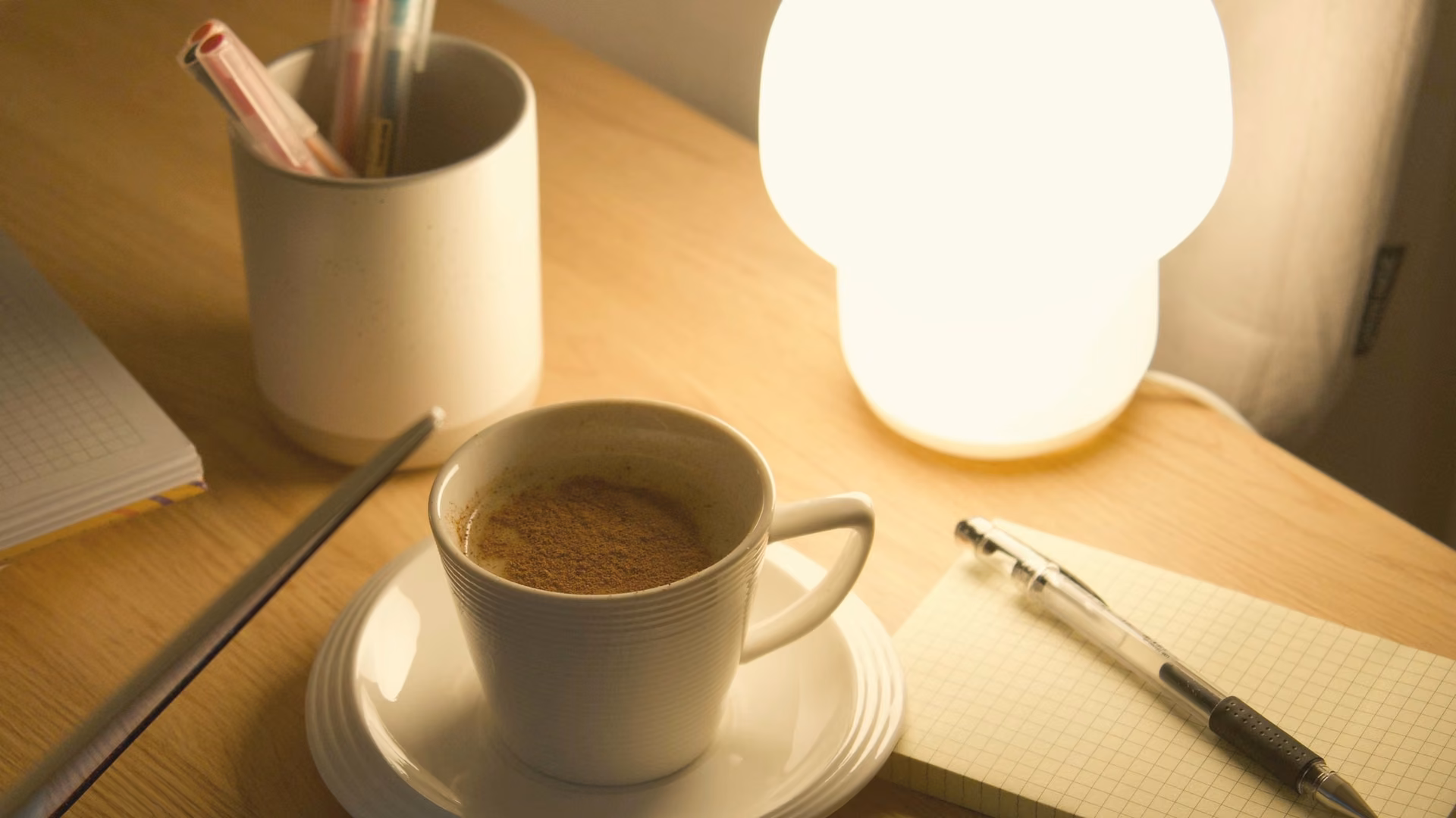 Licensed stock photo (illustrative): glowing mushroom lamp over a coffee cup, notepad and pen on a wood desk