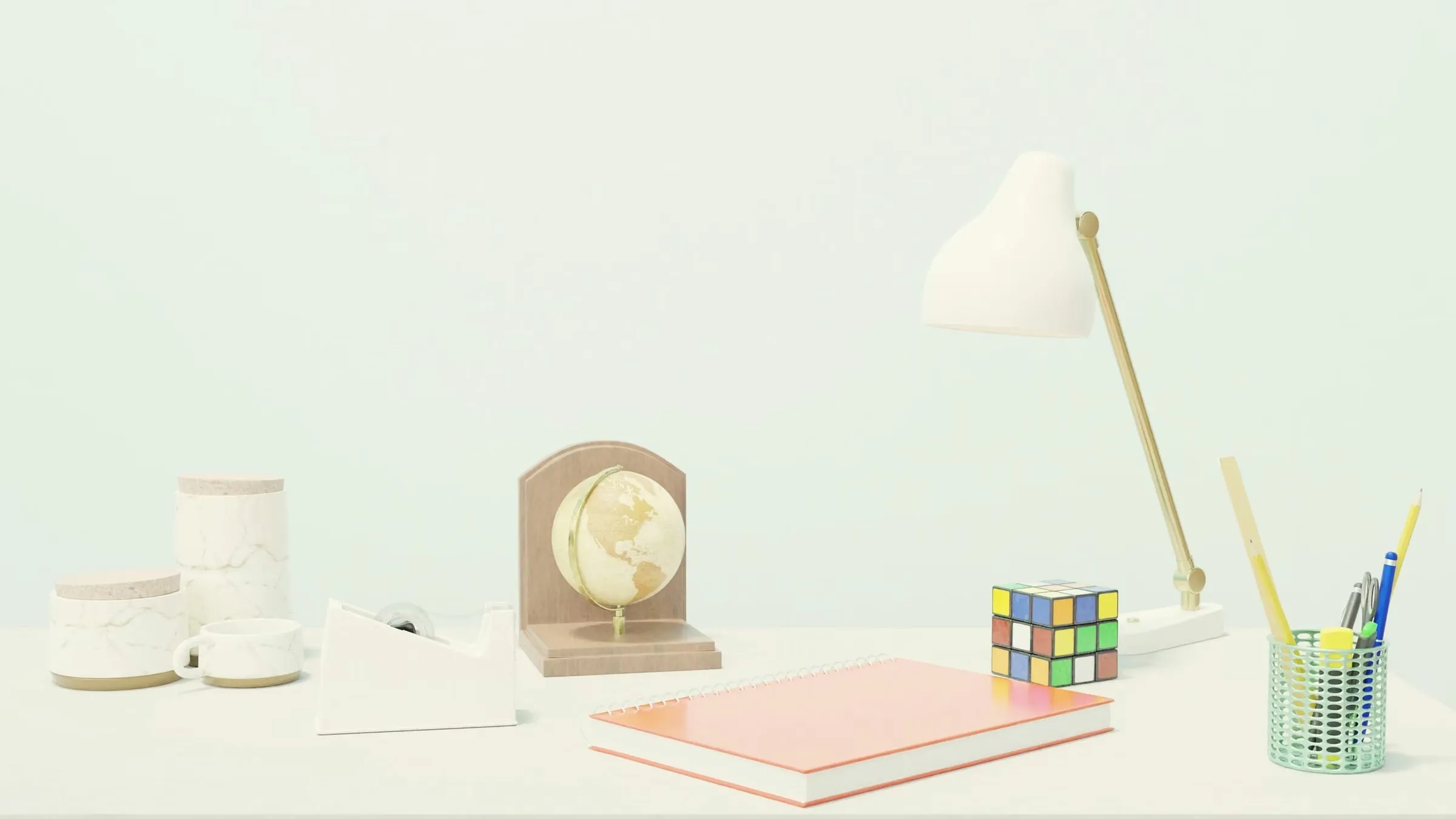 Brass-and-white desk lamp on a pale mint desk beside stationery