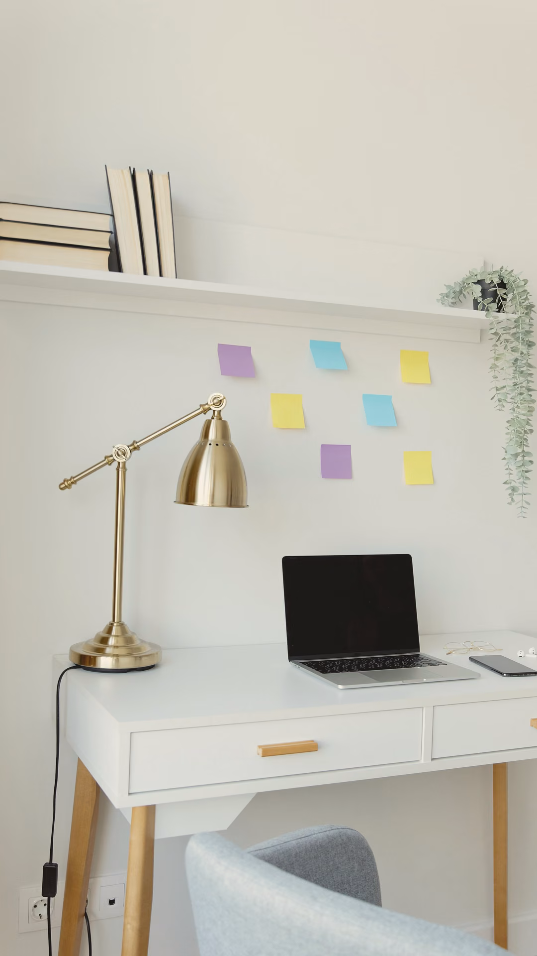 White home-office desk with a brass arm lamp and a laptop