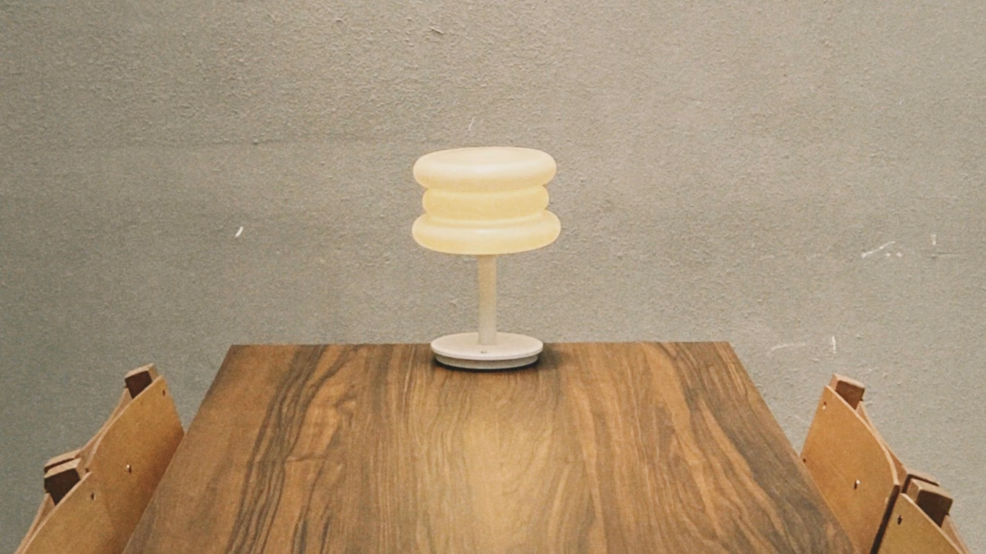 Licensed stock photo (illustrative): small cream lamp on a long wooden table against a plain grey wall