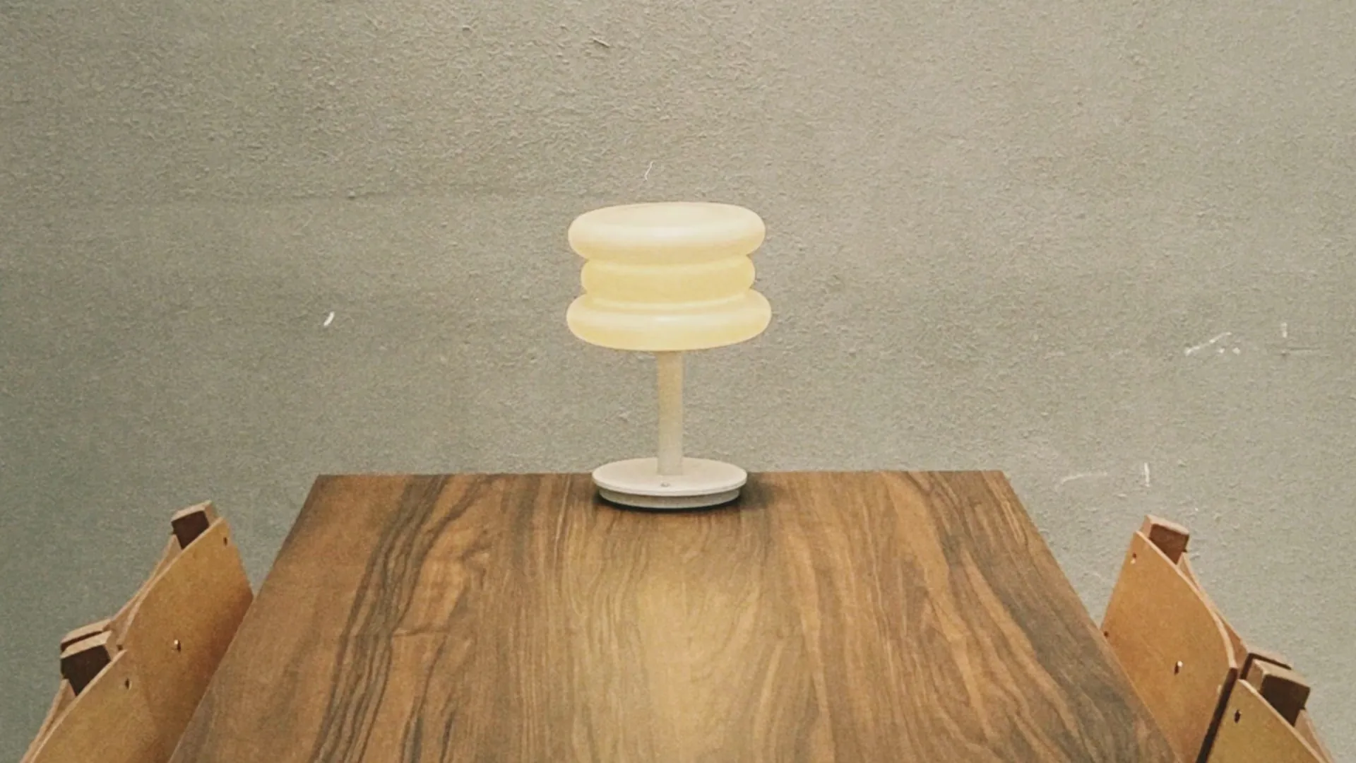 Licensed stock photo (illustrative): small cream lamp on a long wooden table against a plain grey wall