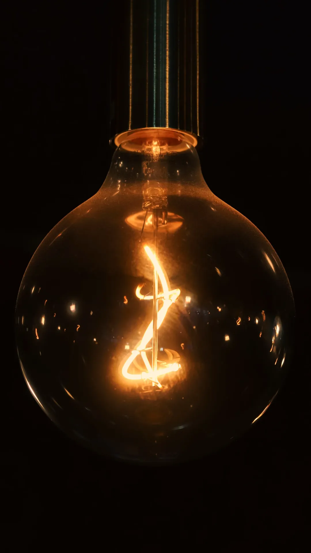 Glowing globe filament bulb against a black background
